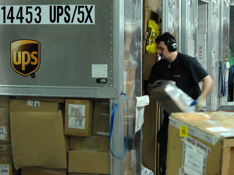 Arbeiter entladen am Flughafen Koeln/Bonn im Distributionszentrum des Paketdienstes United Parcel Service (UPS) Pakete aus Flugzeugcontainern.