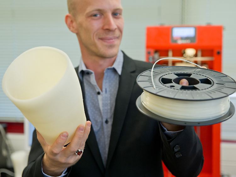 Christian Zagel mit dem Entwurf einer Beinprothese (l) aus dem 3D-Drucker sowie einer Rolle selbst hergestellter Plastikschnur für den Drucker.