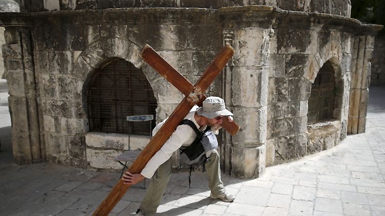 Ein Tourist hat ein Mietkreuz ausgeliehen und geht damit durch die Altstadt. Viele wollen damit den Leidensweg Christi nachempfinden.