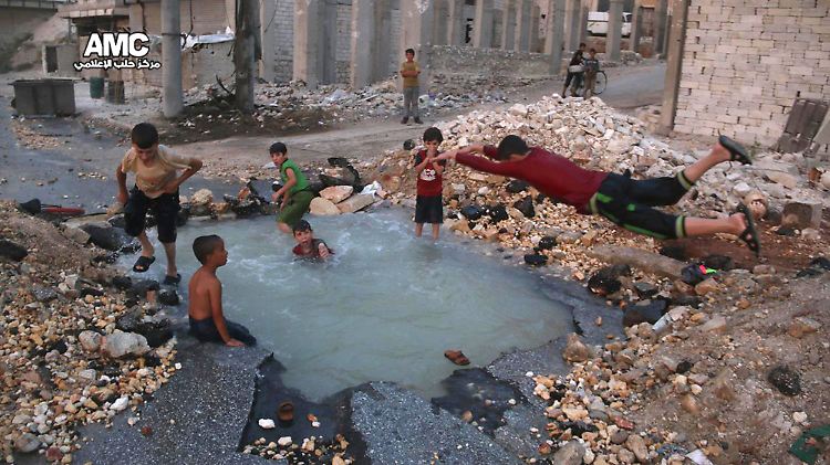 Kinder spielen während der Waffenruhe in Aleppo in einem mit Wasser gefüllten Raketenkrater.