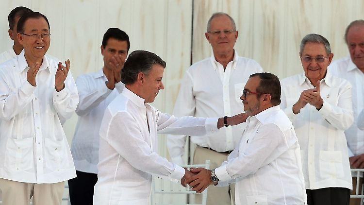 Im Beisein von UN-Generalsekretär Ban Ki Moon (l.) und Kubas Präsident Raúl Castro (r.) schüttelt Präsident Juan Manuel Santos (3.v.l.) nach den Unterschriften die Hand von Farc-Chef "Timochenko".