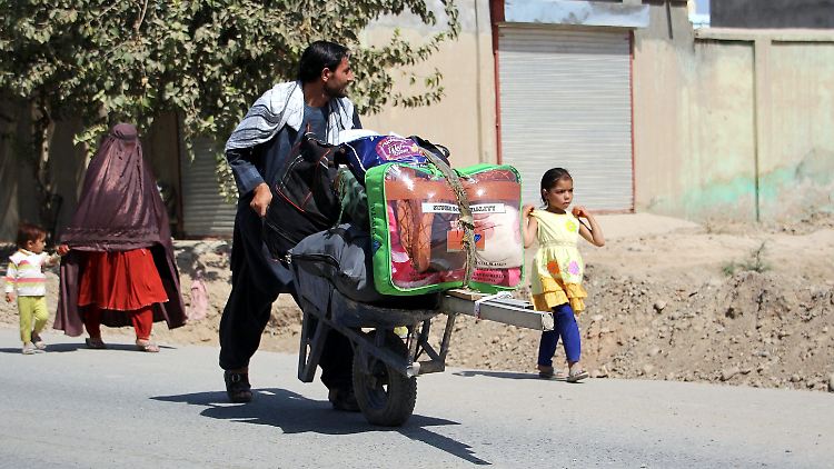 Mit gepackter Schubkarre verlässt eine Familie die Stadt, um den Kämpfen zwischen Taliban und afghanischen Sicherheitskräften zu entkommen.