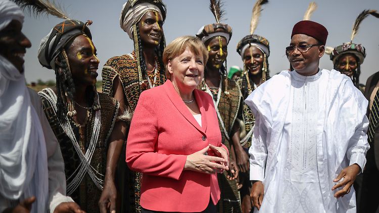Bundeskanzlerin Merkel wird im Niger von Präsident Issoufou sowie Männern vom Stamm der Wodaabe begrüßt.