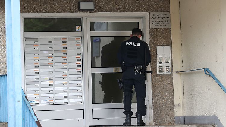 Ein Polizist vor der Wohnungstür eines Verdächtigen.