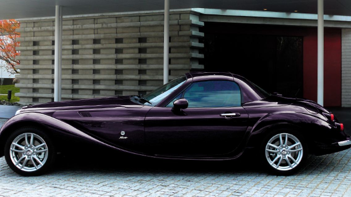 Vielleicht beim dritten Hinsehen kann man allerdings erkennen, dass eine ganz moderne Basis unter seiner ausladenden Blechhaut steckt: Ein Mazda MX-5 verbirgt sich unter der von Mitsuoka drastisch modifizierten Karosserie.
