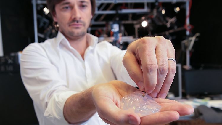 Der Wissenschaftler Grégoire Courtine vom Swiss Federal Institute of Technology in Lausanne mit einem Silikon-Modell eines Primaten-Gehirns und einem Gehirn-Implantat.