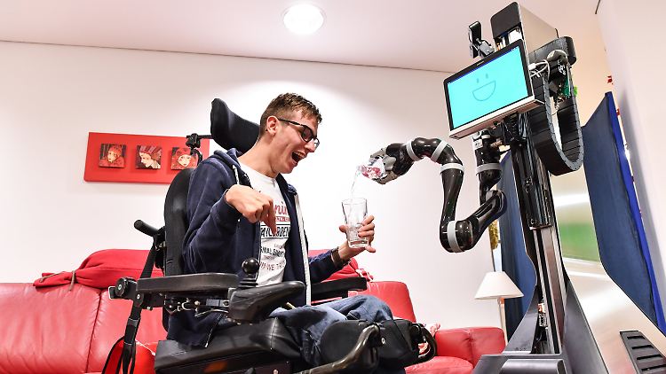 Roboter Marvin schenkt Rollstuhlfahrer Marvin Thurner ein Glas Wasser ein.