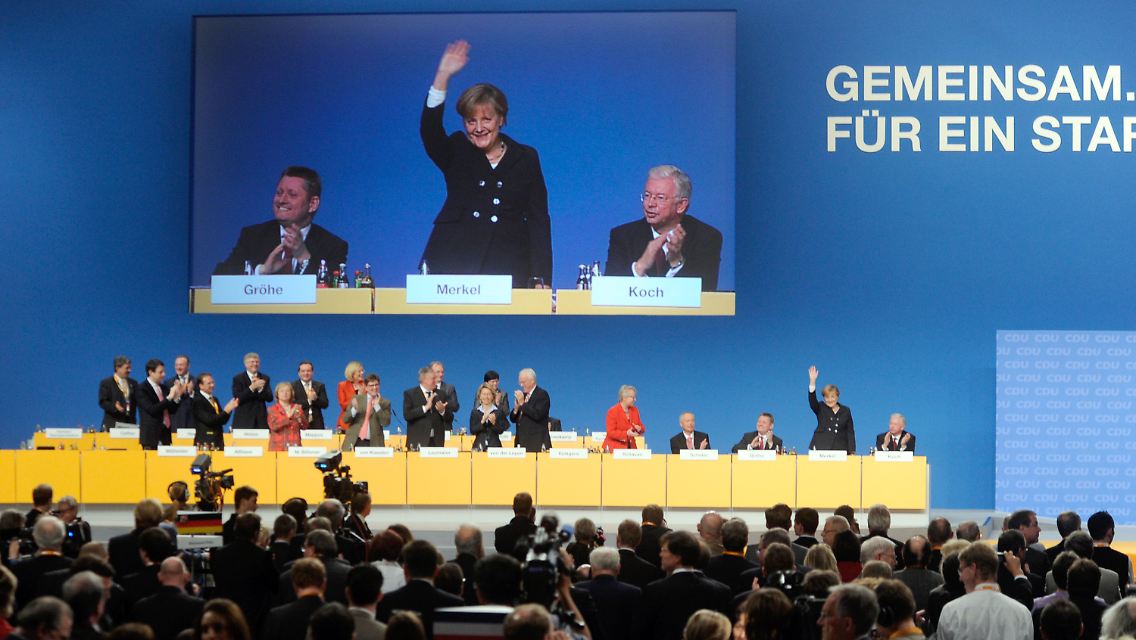 Überlebensgroß: Merkel winkt den Delegierten.
