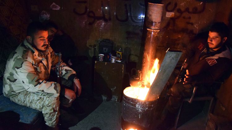 Syrische Regierungssoldaten wärmen sich an einem Feuer.