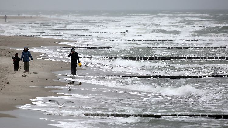 Spaziergänger sind an der aufgewühlten Ostsee in Graal-Müritz in Mecklenburg-Vopommern unterwegs.
