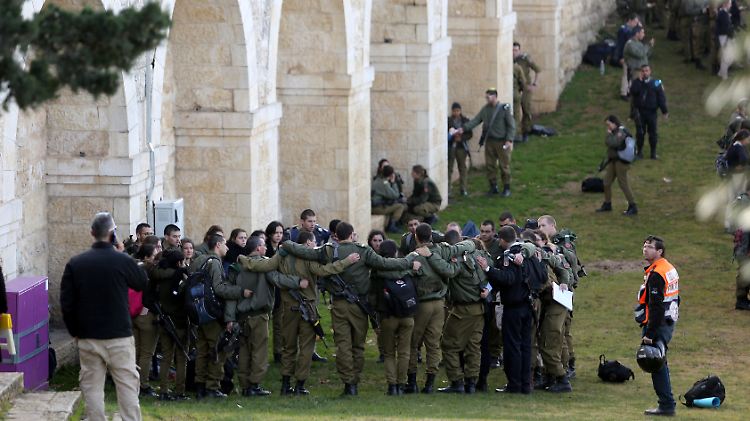 Israelische Soldaten spenden sich nur wenige Meter vom Tatort entfernt gegenseitig Trost.