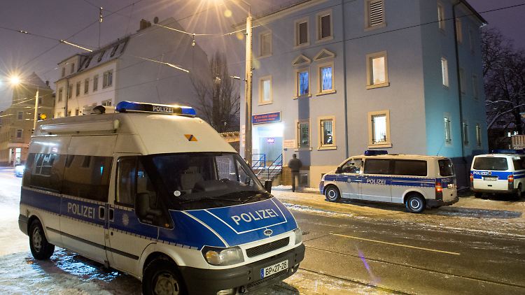 Mehrere Einsatzwagen sichern im Zuge der Razzia dieses Wohn- und Geschäftshaus in Dresden ab.