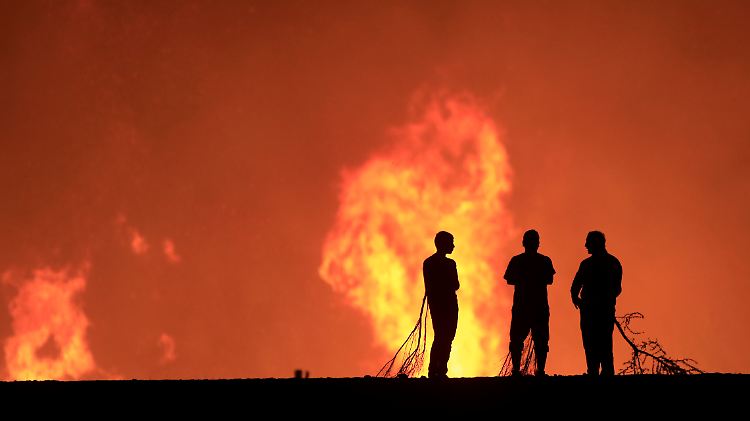 Bewohner von Pumanque starren zusammen mit Feuerwerleuten fassungslos in die Flammen.