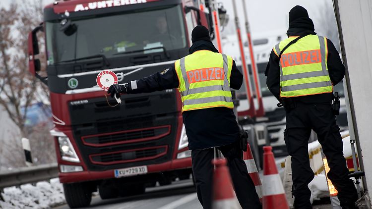 Zwei Polizisten kontrollieren auf der A93 einen Lkw, der aus Österreich nach Deutschland einreisen.