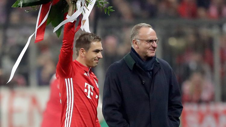 Bayern's Philipp Lahm waves on the field with flowers besides Bayern CEO Karlheinz Rummenigge prior to the German Soccer Cup match between FC Bayern Munich and VfL Wolfsburg at the Allianz Arena stadium in Munich, Germany, Tuesday, Feb. 7, 2017. (AP Photo/Matthias Schrader)  