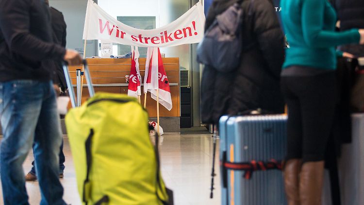 "Wir streiken" steht am 08.02.2017 im Terminal 3 am Flughafen in Stuttgart (Baden-Württemberg) auf einem Banner des Bodenpersonals der Stuttgart Ground Services (SGS), während davor Passagiere lange auf den Check-In für ihre Koffer warten. Wegen der Warnstreiks kommt es heute an den Flughäfen in Stuttgart, Berlin und Hamburg zu Ausfällen und starken Verzögerungen. Foto: Christoph Schmidt/dpa +++(c) dpa - Bildfunk+++