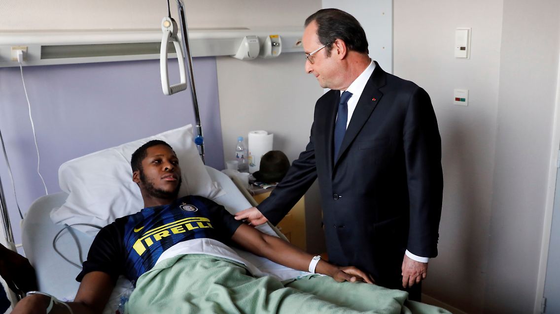 In this photo dated Tuesday, Feb. 7, 2017, provided by Le Parisien, France's President Francois Hollande, right, stands next to alleged victim, identified only by his first name, Theo, at Robert Ballanger hospital in Aulnay-sous-Bois, north of Paris, France. Violence in suburbs northeast of Paris have now spread to at least five towns, erupting after a young black man was allegedly sodomized with a police officer's baton last week, during an identity check. One officer was charged Sunday with aggravated rape and three others were charged with aggravated assault. (Arnaud Journois/Le Parisien via AP)