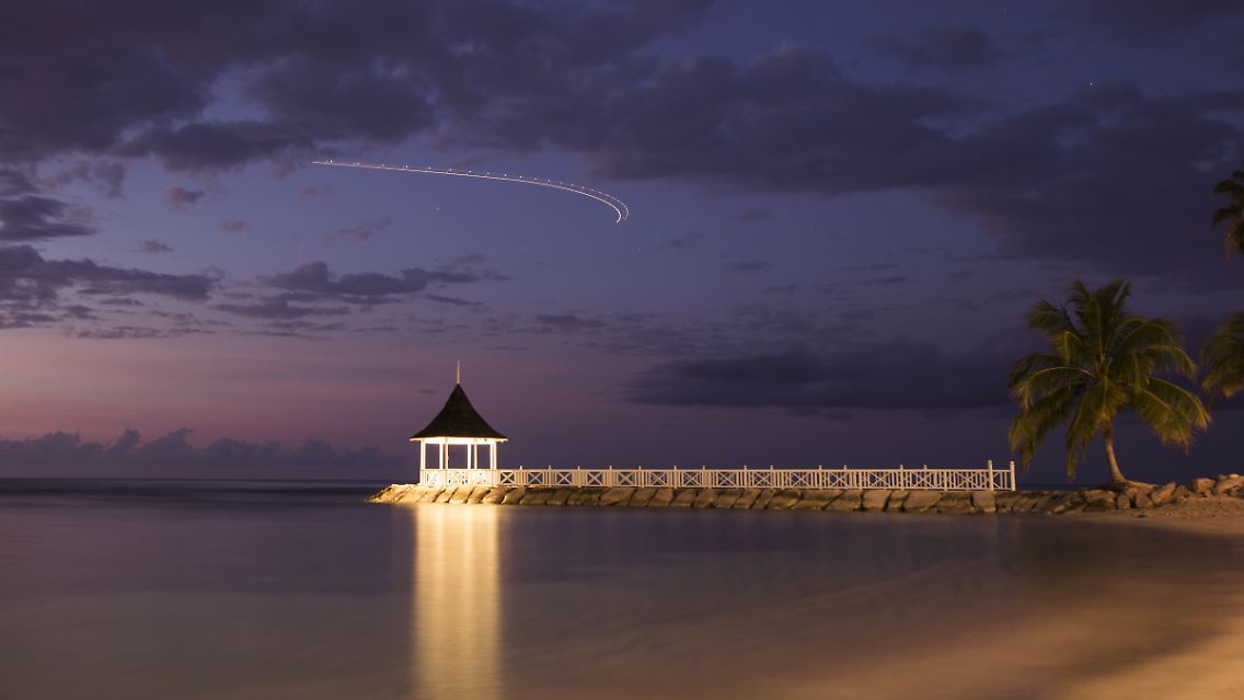 Die Langzeitbelichtung zeigt den Lichtstreif eines startenden Flugzeugs am abendlichen Himmel. Irgendwie blickt man ihm gerne nach, dem deutschen Ferienflieger. (Bildlegenden-Texte: A. Augustin)