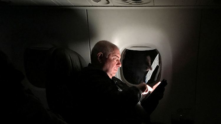 Ein Mann schaut während eines Fluges auf sein Tablet. Das soll auf bestimmten Flügen aus dem Nahen Osten in die USA bald nicht mehr möglich sein.