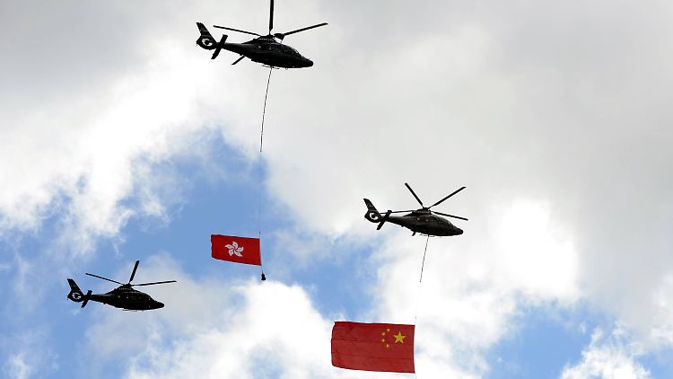 Helikopter haben zur  15-Jahres-Feier der Übergabe der ehemaligen britischen Kolonie im Jahr 2012 die Flaggen Hongkongs (l.) und Chinas im Schlepptau.