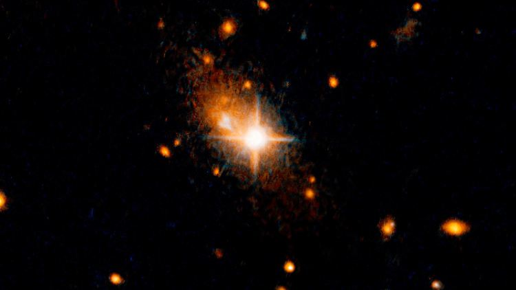 Der helle, sternenähnliche Quasar (Bildmitte), der der aktive Kern einer Galaxie ist, ist vor seiner Heimatgalaxie zu sehen.