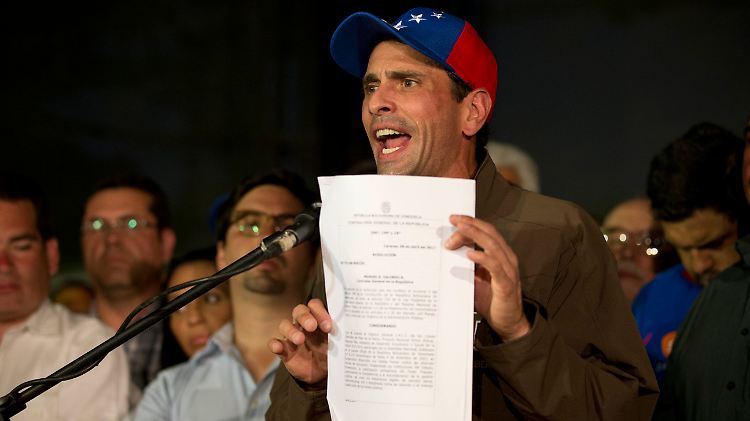 Oppositionsführer Capriles hält bei einer Rede vor Unterstützern das Dokument hoch, dass es ihm auf 15 Jahre verbietet, öffentliche Ämter anzunehmen.
