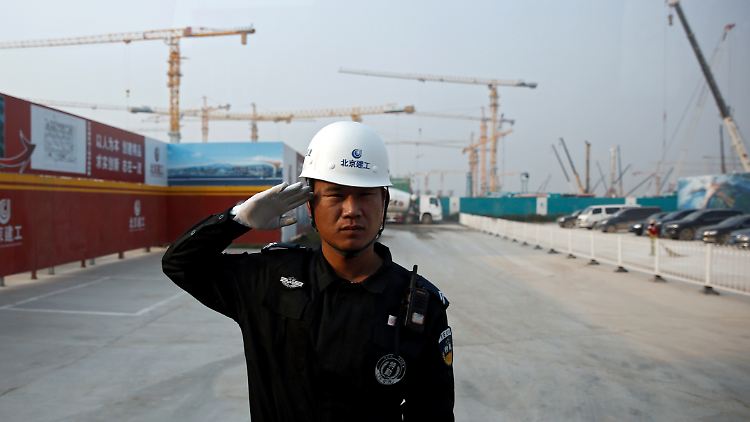 Ein Sicherheitsbeamter salutiert vor der Baustelle des neuen Flughafens in Peking.