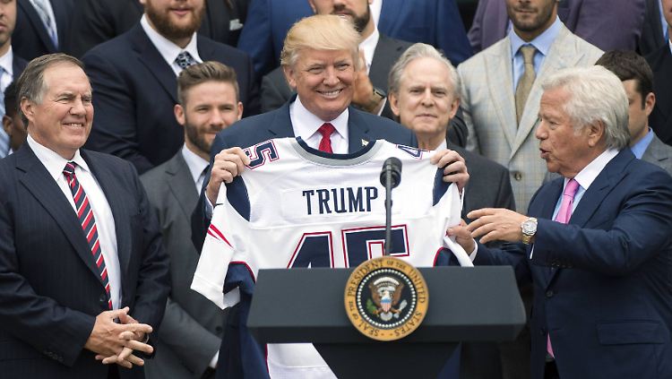 Donald Trump präsentiert mit seinem Donald-Trump-Lachen sein Donald-Trump-Trikot.