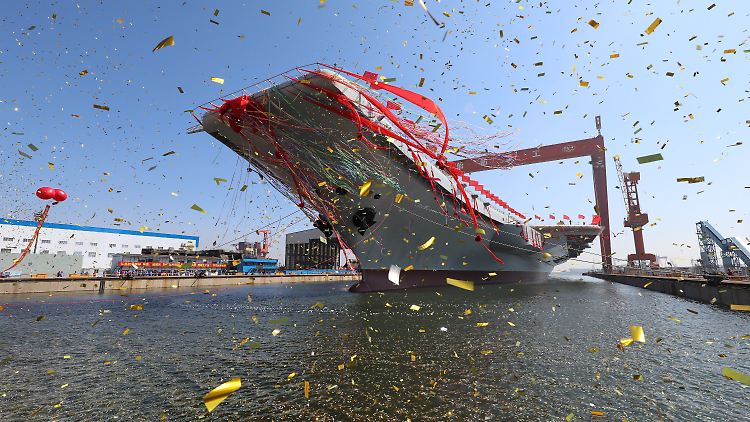 Mit gigantischen roten Fahnen geschmückt verlässt Chinas neuester Flugzeugträger sein Dock in Dalian.