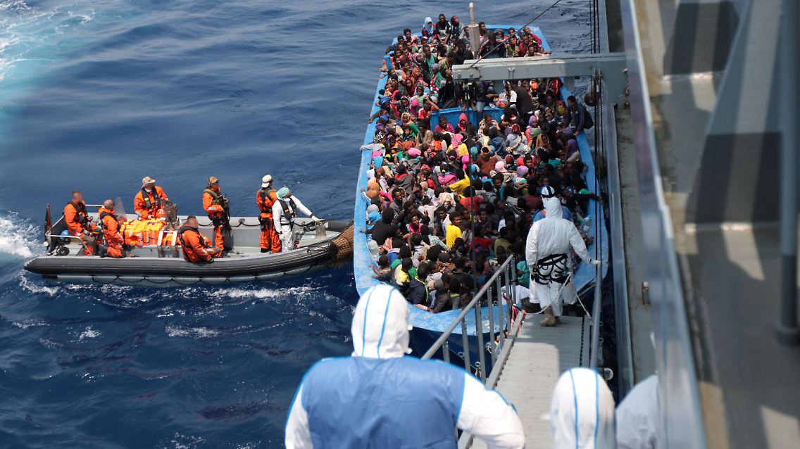 Auf diesem Bild sind Soldaten der Bundeswehr zu sehen, die Flüchtlinge aus einem überladenen Boot retten.