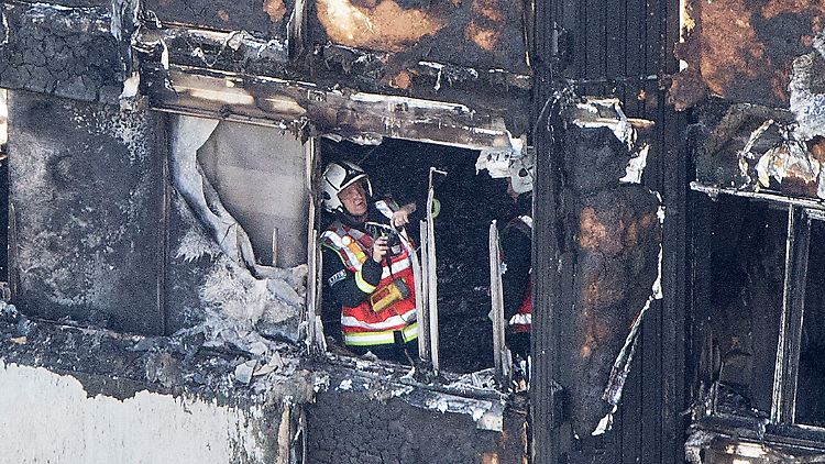 Ein Feuerwehrmann macht Aufnahmen der verbrannten Fassade. Das Feuer konnte sich über die Außenhaut des Hochhauses schnell verbreiten.