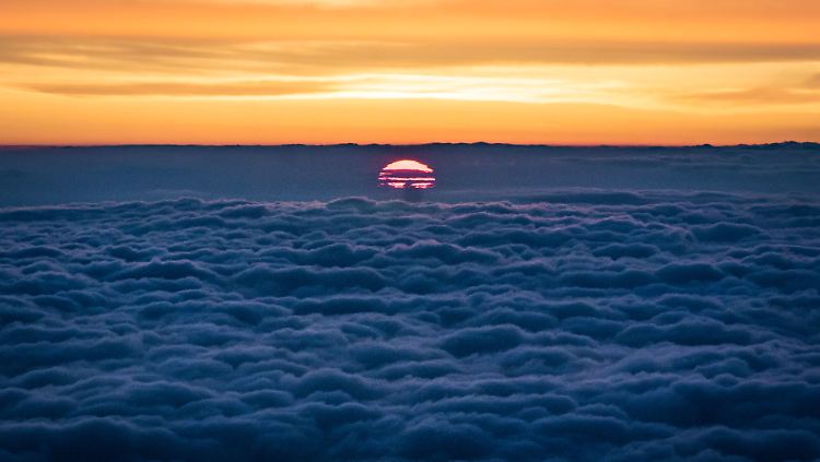 Die Sonne steigt über der Rhein-Main-Ebene aus einer Wolkenschicht empor - fotografiert aus einem Jumbojet im Landeanflug auf den Flughafen Frankfurt.
