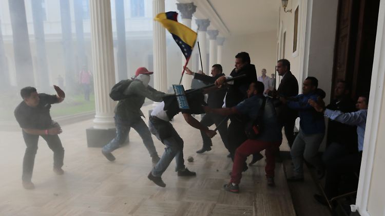 Nach Angaben der Opposition sollen Polizisten den Maduro-Anhängern die Tore zum Parlament geöffnet haben.