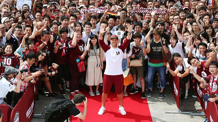 Unter Jubel wird Lukas Podolski von hunderten japanischen Fans in Kobe empfangen.