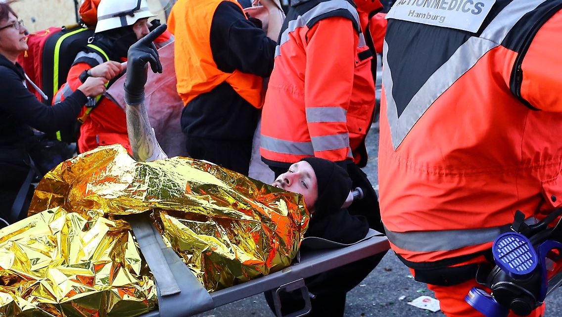 Ein Verletzter zeigt den Mittelfinger, als er von Sanitätern abtransportiert wird.
