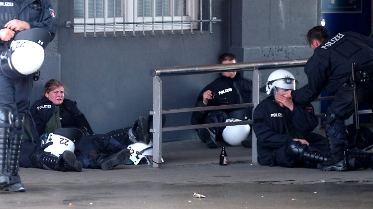 Völlig erschöpfte Polizisten sitzen nach einem Einsatz nahe der Hamburger Landungsbrücken zusammen.