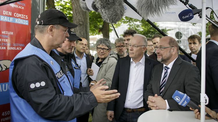 Martin Schulz im Gespräch mit Polizisten, die am Rande des Schanzenviertels an einem Infostand stehen.