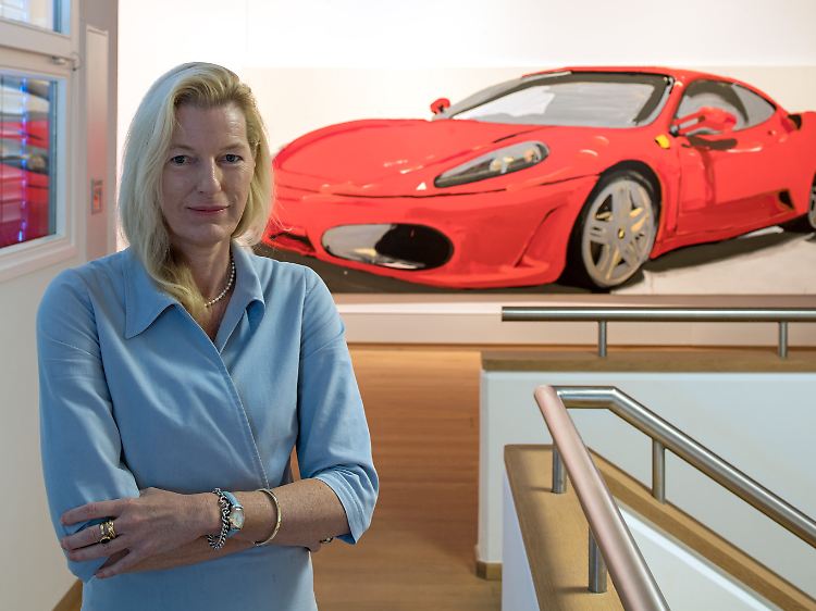 Die Kuratorin Annette Vogel ist für Idee und Konzeption des Ausstellungsprojektes verantwortlich. Im Hintergrund: Gemälde aus Lack und Acryl "Ferrari F430, 2005" von Tatjana Doll.