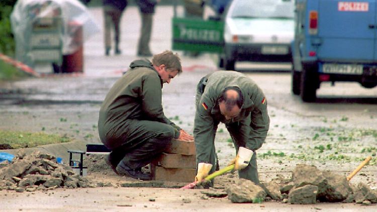 Zwei Spezialisten der Bundeswehr untersuchen im Jahr 1996 den Krater im Asphalt, der nach dem Granatenanschlag Kaserne entstanden war.
