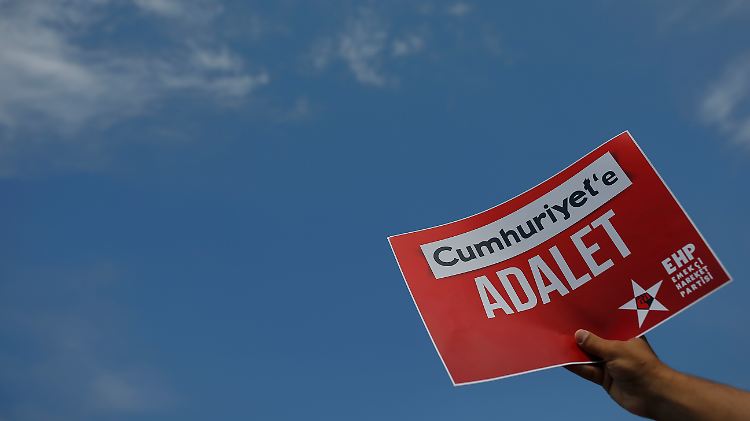 Ein Aktivist hält vor dem Gericht in Istanbul ein Schild mit dem Appell "Gerechtigkeit für "Cumhuriyet" in die Höhe.