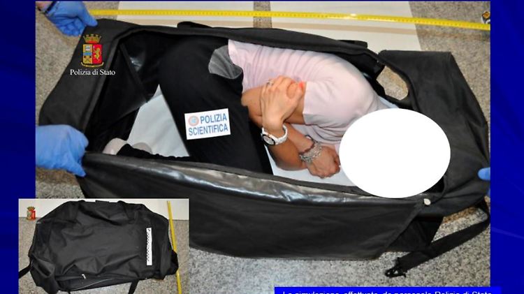 Ein Polizist stellt nach, wie die Frau in einer großen Reisetasche transportiert worden sein soll.