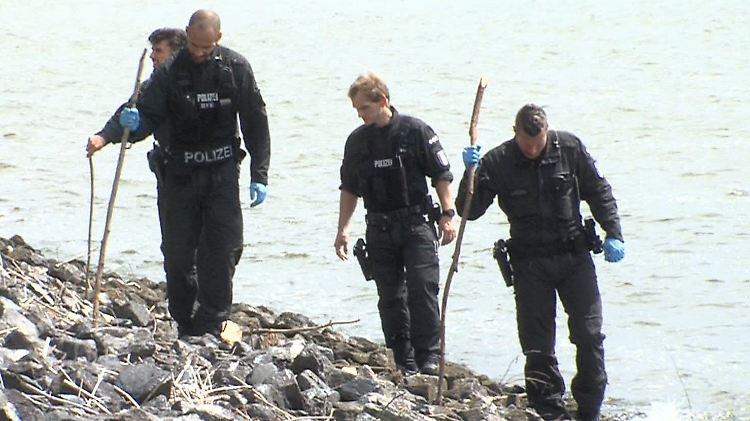 Polizisten suchen den Elbstrand nach weiteren Hinweisen ab. 