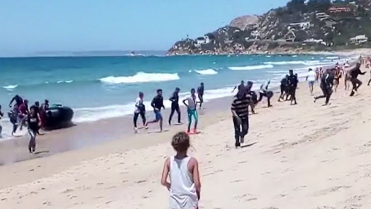 Eine Frau beobachtet, wie Flüchtlinge mit einem Boot in der Provinz Cadiz ankommen.