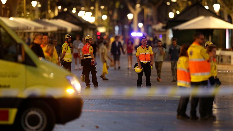 Rettungskräfte stehen auf einer abgesperrten Straße in Barcelona.
