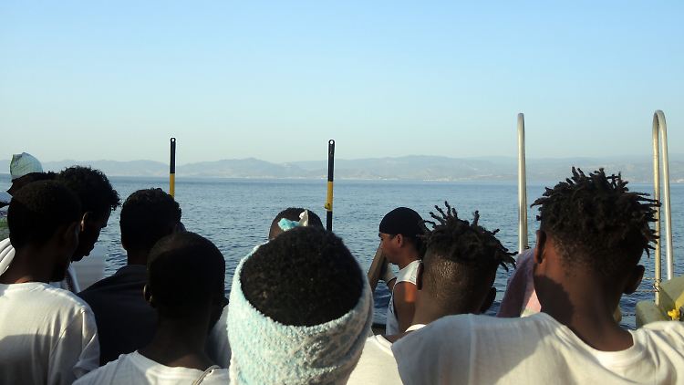 Flüchtlinge blicken von einem Rettungsboot aus auf die italienische Küste.