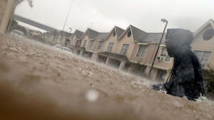 Ein Bewohner watet in Houston (Texas) durch die Fluten, wo eigentlich eine Straße zu sehen ist.