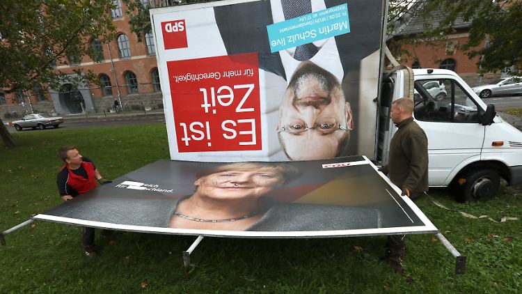 Jetzt wird aufgeräumt: Arbeiter beseitigen in Berlin Wahlplakate mit den Konterfeis von Schulz und Merkel.