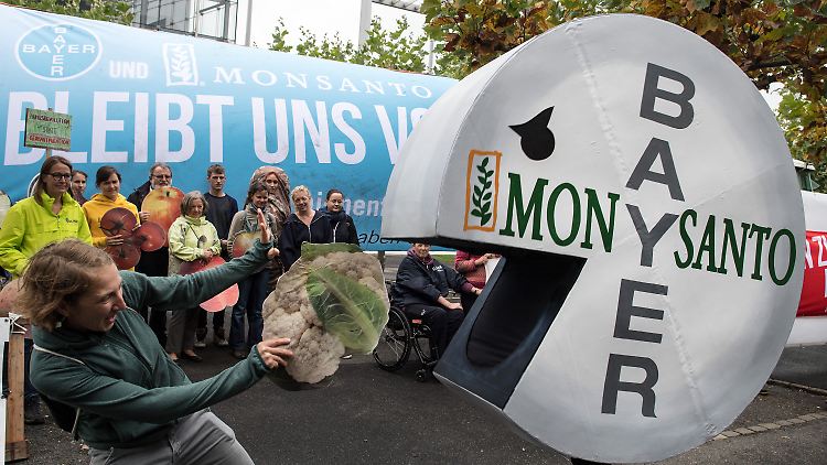Eine Demonstrantin wehrt vor der Bayer-Konzernzentrale in Leverkusen einen Pac-Man im Bayer-Monsanto-Look ab.