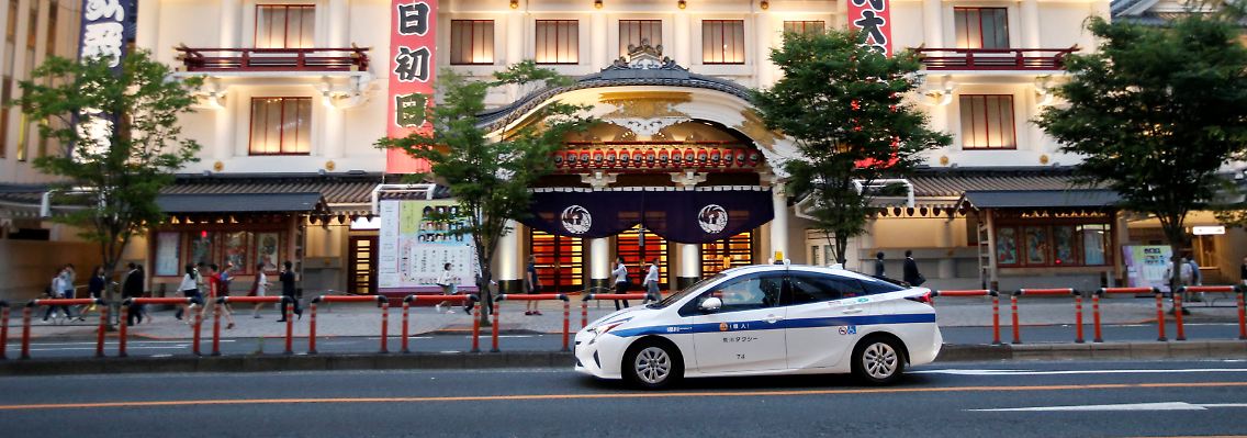 Straßenszene in Tokio: Ein Hybrid-Taxi von Toyota fährt vor dem Kabuki-Theater vor.