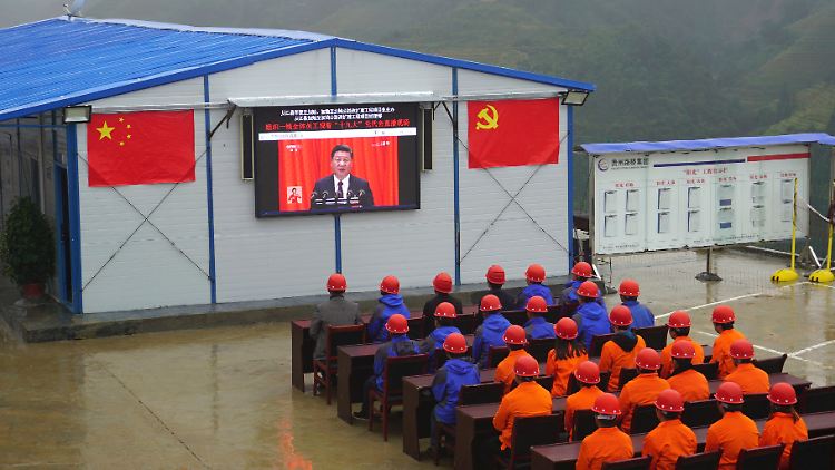 Bauarbeiter lauschen Xis Parteitagsrede. 